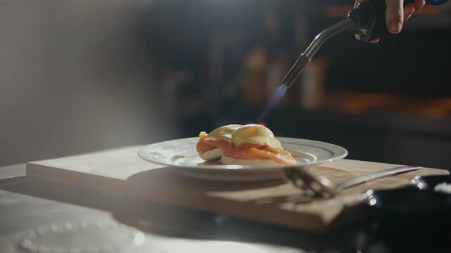 Chef expertly uses torch to perfect dish. Soft light beams reveal elegant plating. Warm tones suggest upscale dining experience. Ideal for restaurant promotions or culinary showcases