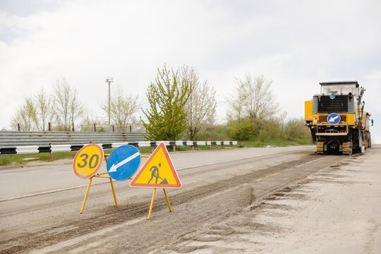 Roadwork Signs and Asphalt Milling Machine on Highway, Indicating Construction Ahead, Safety First