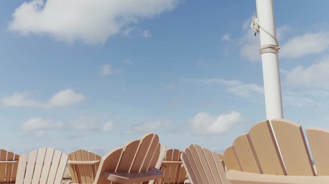 Sunlit beach chairs face the sea under blue skies. No people present. Quiet, empty, peaceful atmosphere. Ideal for travel, vacation, or summer relaxation scenes