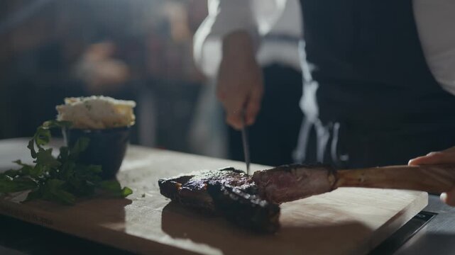 Chef holds knife near grilled steak. Cutting motion suggests precision and care. Soft lighting enhances rustic, culinary ambiance. Perfect for food, dining, or gourmet restaurant scenes