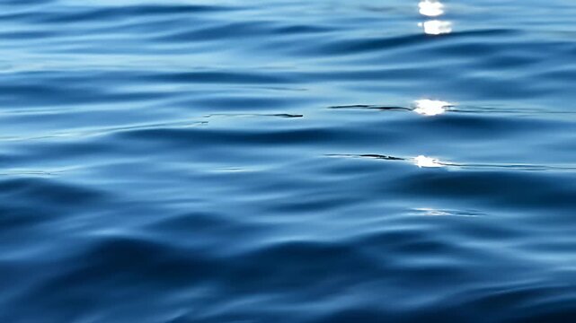 Blue water ripples with sparkling sunlight reflecting on surface
