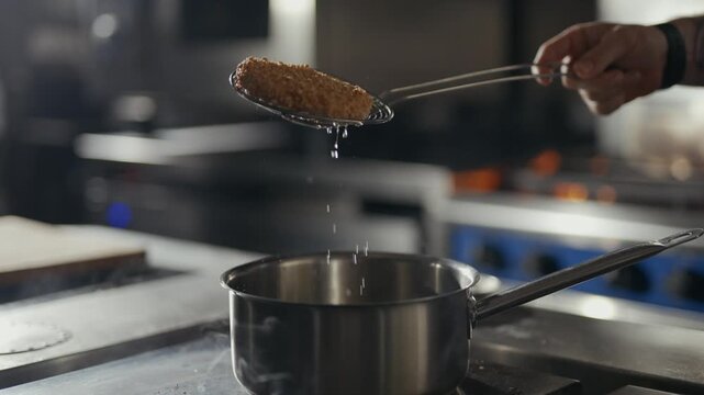 Hand stirs pot on professional stove. Cook lifts golden food with ladle, dripping liquid. Steam rises, hinting at fresh, savory dish. Ideal for culinary, restaurant, or food preparation scenes