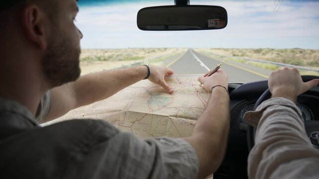 Man navigating a road trip through Namibia desert with a map while his friend drives car, capturing essence of adventure and exploration in Africa