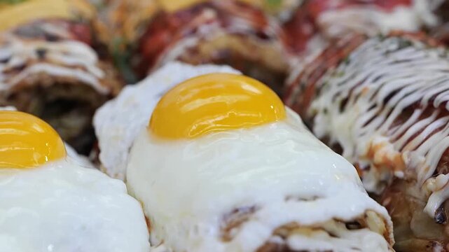 High-angle, macro shot of perfectly cooked sunny-side-up eggs with crispy, golden-brown edges and vibrant, runny orange yolks resting on a bed of seasoned food.