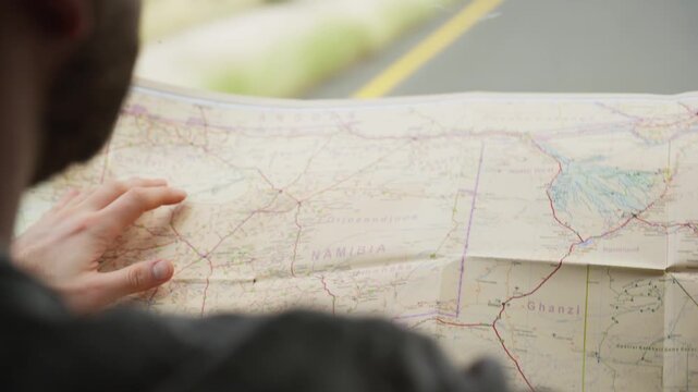 Close up of a traveler's hands drawing route on a map of Namibia. Adventurous man planning road trip itinerary in Africa. Concept of exploration and vacation