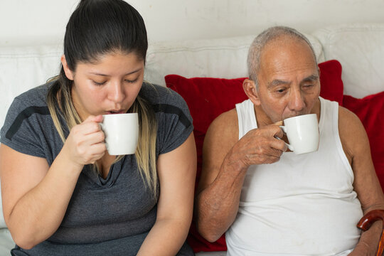 Granddaughter and elderly grandfather drinking coffee together sharing a peaceful moment at home