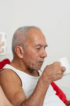 Elderly man carefully drinking coffee alone showing independence despite visual impairme