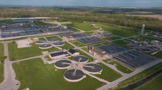 Aerial view of a large water treatment facility featuring circular clarifiers and rectangular filtration basins surrounded by green fields in Indianapolis, Indiana, United States.