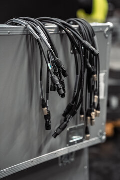 XLR audio and power cables draped over silver flight case in backstage event production area, symbolizing live concert infrastructure, touring and professional stage technology