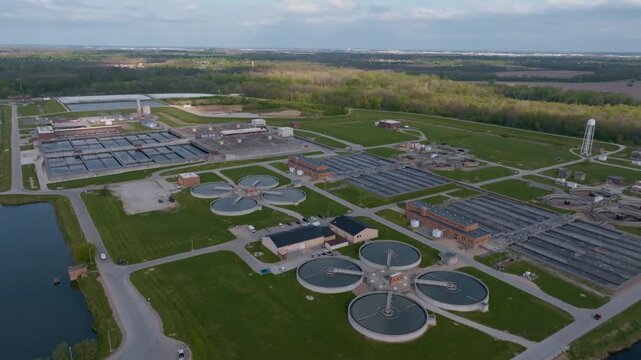 Aerial view of a large water treatment facility featuring circular clarifiers and industrial buildings surrounded by green fields in Indianapolis, Indiana, United States.