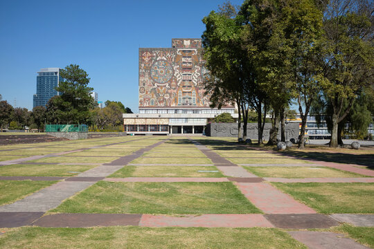 The Universidad Nacional Aut&oacute;noma de M&eacute;xico - UNAM - building in Mexico City features large-scale murals depicting cultural and historical themes under clear blue skies.
