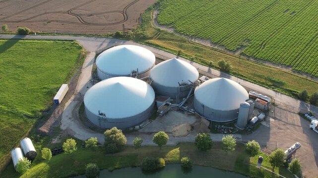 Aerial view of agricultural complex of barns and biogas production domes and storage tanks, bio renewable energy generation from rural panorama landscape Europe