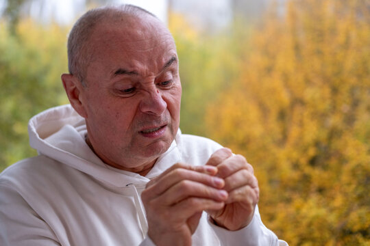 Senior man picking hangnails on fingers, close-up hands, focused expression, nervous habit and stress behavior concept, elderly male grooming nails, unhealthy repetitive action, Anxiety and tension
