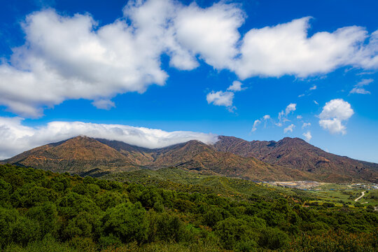 Paisaje de monta&ntilde;a m&iacute;stica en Sierra Crestellina Casares con nubes bajas abrazando la cumbre bajo cielo azul concepto de libertad esperanza purificaci&oacute;n y naturaleza salvaje m&iacute;stica en horizonte infin