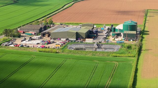 Aerial view of Bioganix Ltd industrial facility with green silos and processing tanks surrounded by lush green farmland in Brigg, England, United Kingdom.