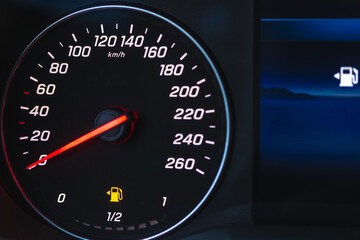 Fototapeta premium Modern car interior dashboard speedometer at night. Low fuel warning light is illuminated on display