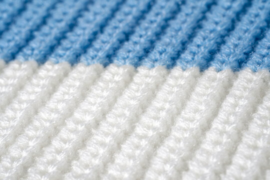 Close-up sweater texture in blue and white colors, knitted striped surface in macro detail. Concept of synthetic textile durability, tactile material quality and practical everyday knitwear