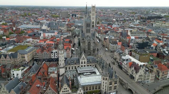 Aerial drone shot of the historic center of Ghent, Belgium. Featuring the Leie river with tour boats, St. Michael&rsquo;s Bridge, and the Gothic architecture of St. Nicholas Church.