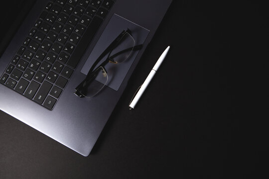 modern laptop and notepad on dark grey background.