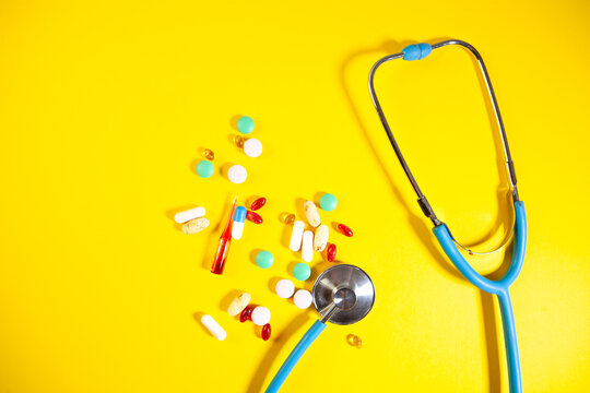 colorful pills and stethoscope on blue background