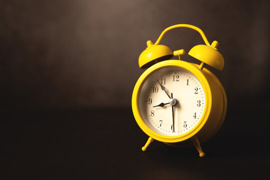 Yellow alarm clock on dark background. Time concept. Copy space.