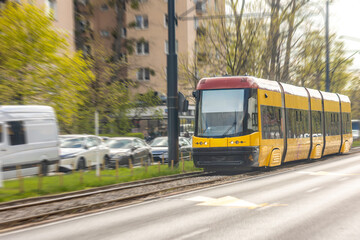 Obraz premium Yellow tram moving along city rails. Urban public transport in daily motion.