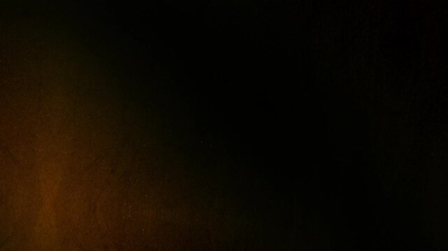 Golden light leaks with dust and scratches on a dark textured background flickering like old film. Nostalgic atmosphere of vintage cinema