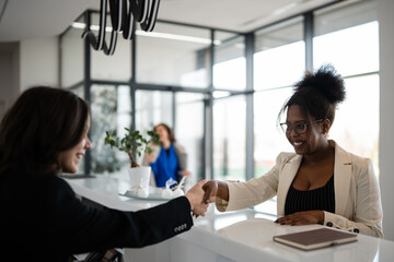 Fototapeta premium Diverse businesswomen shaking hands at office reception desk