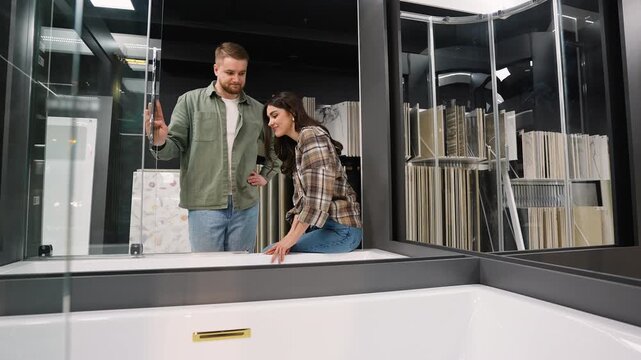 Young couple choosing new bathtub in bathroom supply store