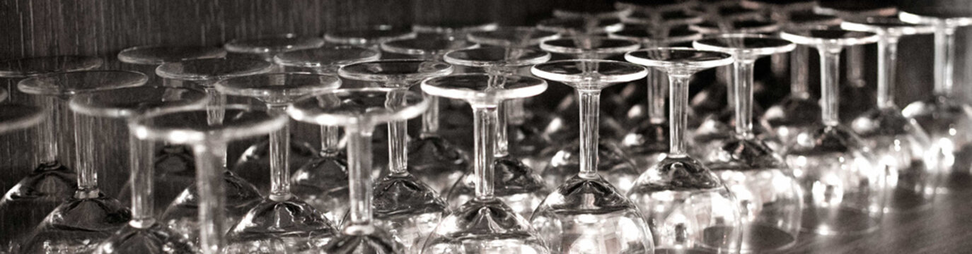 Clean wine glasses arranged upside down on bar shelf interior