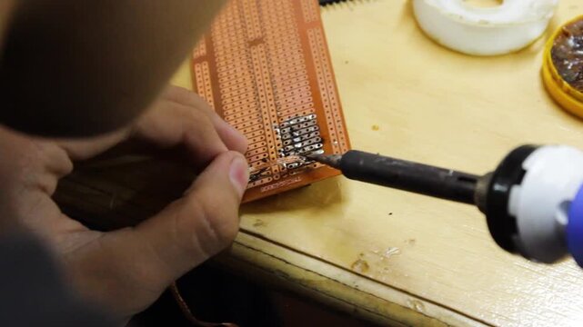 An unrecognizable boy is using two wired circuits to build a robotics project on a laptop inside an educational club in Neiva, Huila, Colombia. Concept of technology and mechatronic