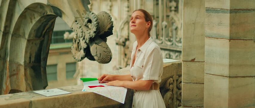 Woman holding map and flag at balcony of Duomo di Milano during Italy trip