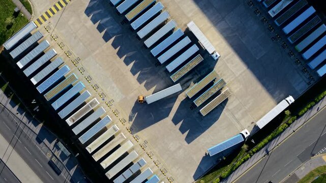 Aerial view of iPort Rail Limited logistics hub featuring rows of parked semi-trailers, loading bays, and surrounding roads under bright sunlight New Rossington, England, United Kingdom.