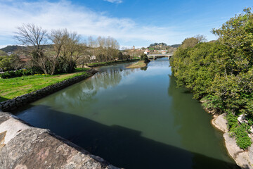 Fototapeta premium Peaceful River Landscape With Bridge and Village Under Blue Sky