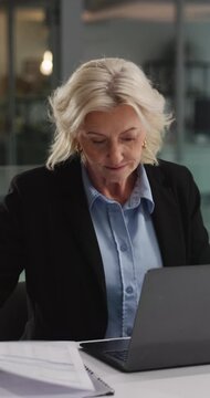 Laptop, document or business woman in office for accounting email, taxes or reading report at night. Computer, mature accountant and paperwork at work for audit, budget review and typing on overtime