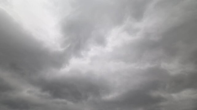 Gloomy storm display. Dark clouds swirl swiftly overhead. Violet storm clouds scatter rapidly across sky. Chaotic swirling grays reveal impending violent tempestuous weather