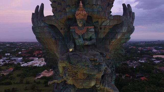 Aerial view of the massive Garuda Wisnu Kencana statue with its intricate details under a purple dusk sky Kecamatan Kuta Selatan, Bali, Indonesia.