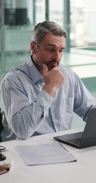 Stress, laptop and businessman in office with documents for finance forecasting with loss prediction. Computer, paperwork and mature financial manager with feedback on investment risk in workplace.