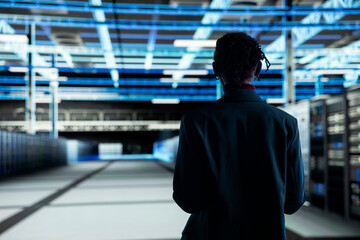 Fototapeta premium Admin walking in data center, configuring server settings with software. IT professional in modern high tech server hub doing maintenance tasks on infrastructure electronics
