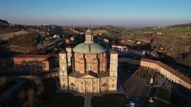 Aerial view of Santuario di Vicoforte with its massive elliptical dome and surrounding hills during sunset Vicoforte, Piedmont, Italy.