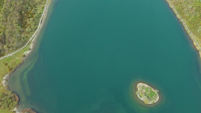 Aerial view of Albert Village Lake with its turquoise water, a small central island, and lush green shorelines Swadlincote, England, United Kingdom.
