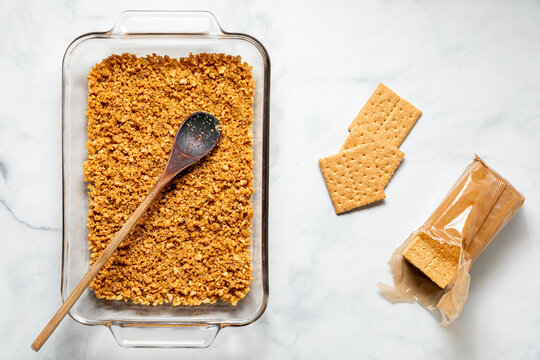 Top down view of a baking dish with a graham cracker crust prior to baking.