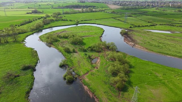 Aerial view of the winding River Trent flowing through lush green meadows and rural landscape in Burton upon Trent, England, United Kingdom.