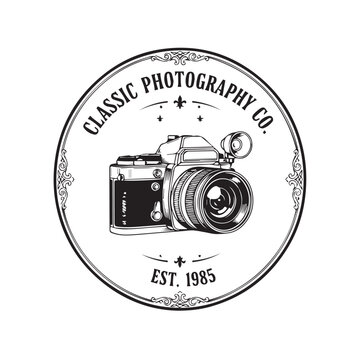 Vintage camera emblem logo featuring a circular badge and classic photography motif.