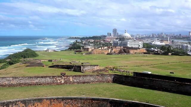 waves crashing on the coast of old san juan puerto rico with view of downtown buildings (scenic caribbean sea travel destination island tourism) beach bay serene peaceful paradise spanish fort 