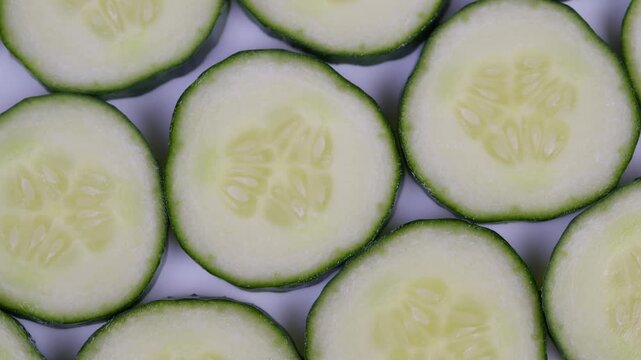 Green cucumber pattern. Flat lay pattern of dewy cucumber slices in green tones. Seamless arrangement of cucumber slices with contrasting flesh and rind in soft lighting