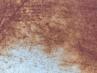 Fototapeta premium Closeup of a weathered rust metal surface showing varied oxidation patterns, brown and orange discoloration, dust accumulation, and uneven corrosion across the deteriorating material.