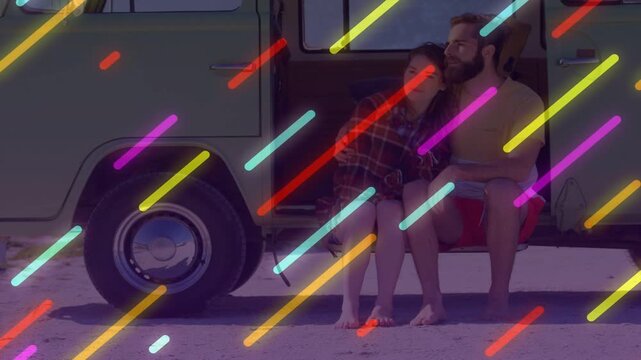 Vertical video: Snuggling couple sitting on green van step neon streaks sweeping, plaid shirt bag