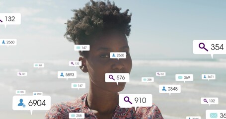 Standing adult woman wearing paisley blouse, stud earring at sandy beach, with floating UI badges