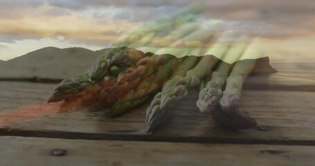 Fototapeta premium Displaying fresh green asparagus spears lying diagonally on wood plank near shore with metal screw